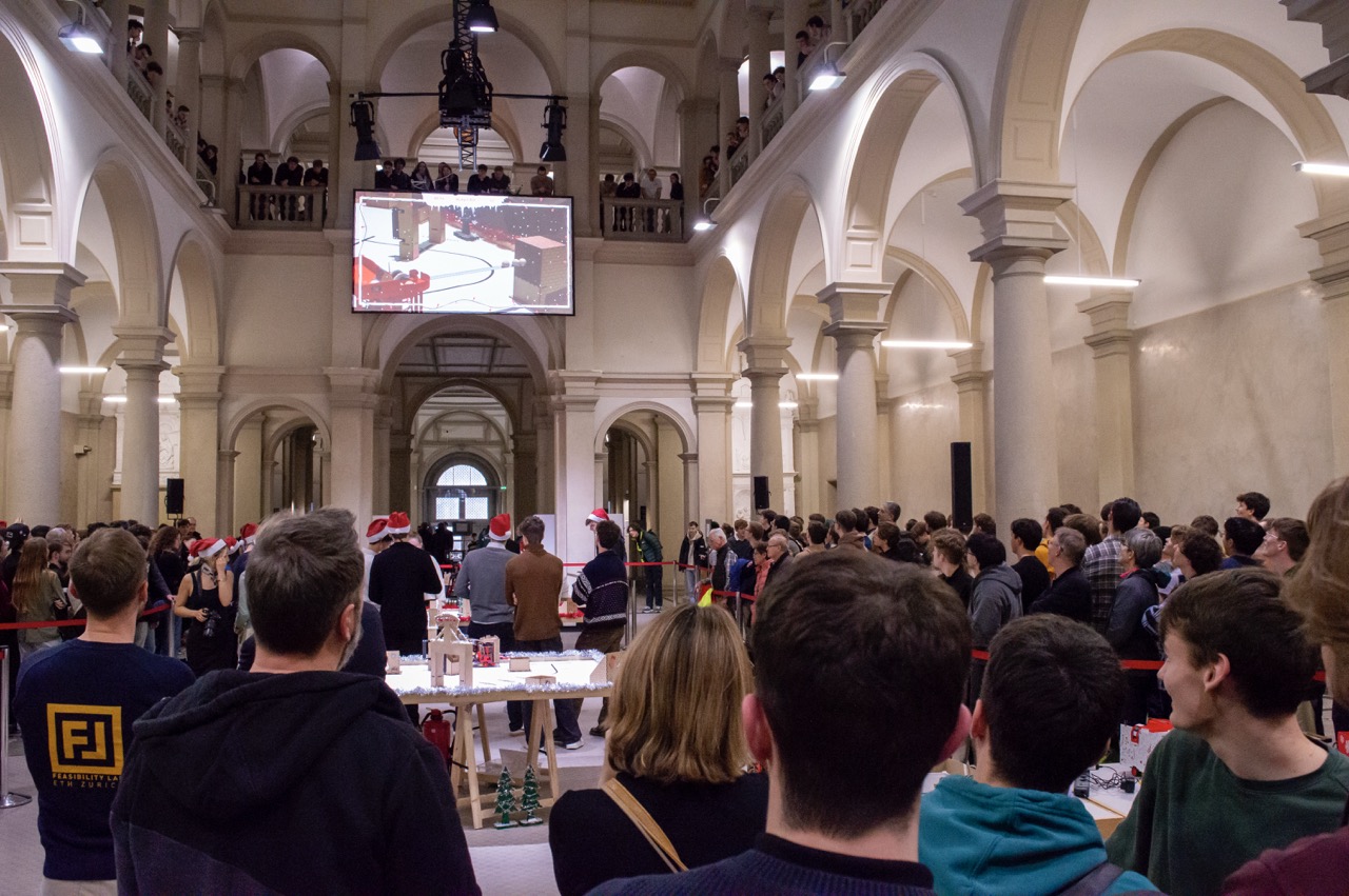 Crowd of pople looking at a big screen at the final event in the ETH main building. 